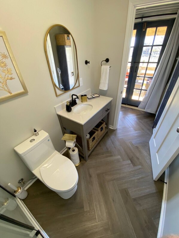 A bathroom with a white toilet, a sink with a gold faucet, a mirror, and a towel hanging on the wall.
