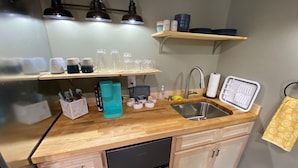 Una cocina compacta con lavavajillas, un lavabo y una encimera con distintos utensilios de cocina.