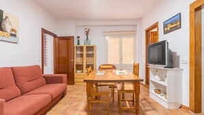 Un salon comprenant un canapé, une table à manger, des chaises, un téléviseur et un meuble.