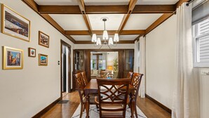 A dining area with wooden chairs and a table, framed pictures on the wall, and a chandelier. - Heritage House in Pittsburgh on Mt Washington - Charming 3BR, 2.5b Sleeps 7+ (Pittsburgh)