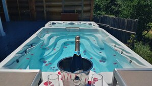 Un bain à remous rempli de pétales de rose, une bouteille de champagne, deux verres et un seau.