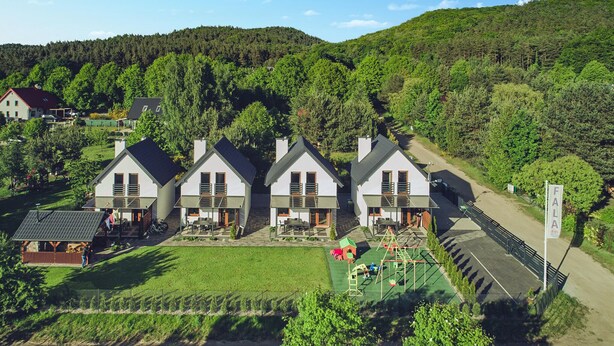 A row of three white houses with dark roofs, set against a backdrop of a lush green hillside. - Awesome home in Lubkowo with WiFi (Lubkowo)
