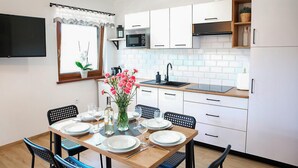 A modern kitchen with white cabinets, a black countertop, and a dining area set for four. - Awesome home in Lubkowo with WiFi (Lubkowo)