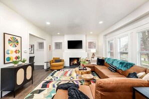 A living room with a fireplace, a sofa, a coffee table, and a TV mounted on the wall.