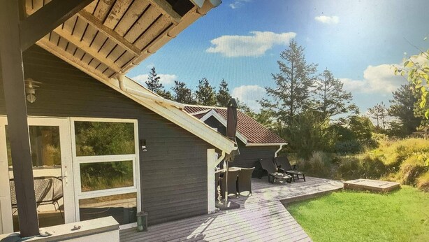 Ein Haus mit einer Holzterrasse, einer überdachten Veranda und Blick auf die umliegenden Bäume.