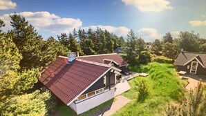 Ein modernes Haus mit geneigtem Dach, umgeben von üppiger Vegetation und Bäumen.