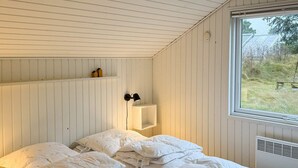 Ein Schlafzimmer mit einem Bett, einem Fenster und einer Wandregal mit zwei Dekorationsobjekten.