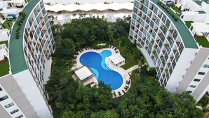 A high-rise hotel with a central swimming pool surrounded by lush greenery and multiple balconies. - Bosques de Ciudad Mayakoba (Playa del Carmen)