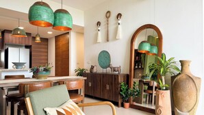 A modern kitchen with wooden cabinets, a dining table, and hanging green pendant lights. - Bosques de Ciudad Mayakoba (Playa del Carmen)