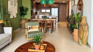 A modern living room with a sofa, a coffee table with a plant, and a dining area with chairs and a table. - Bosques de Ciudad Mayakoba (Playa del Carmen)