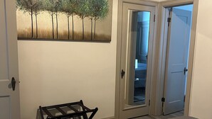 Un dormitorio con cama, un banco, una puerta y un cuadro colgado en la pared.