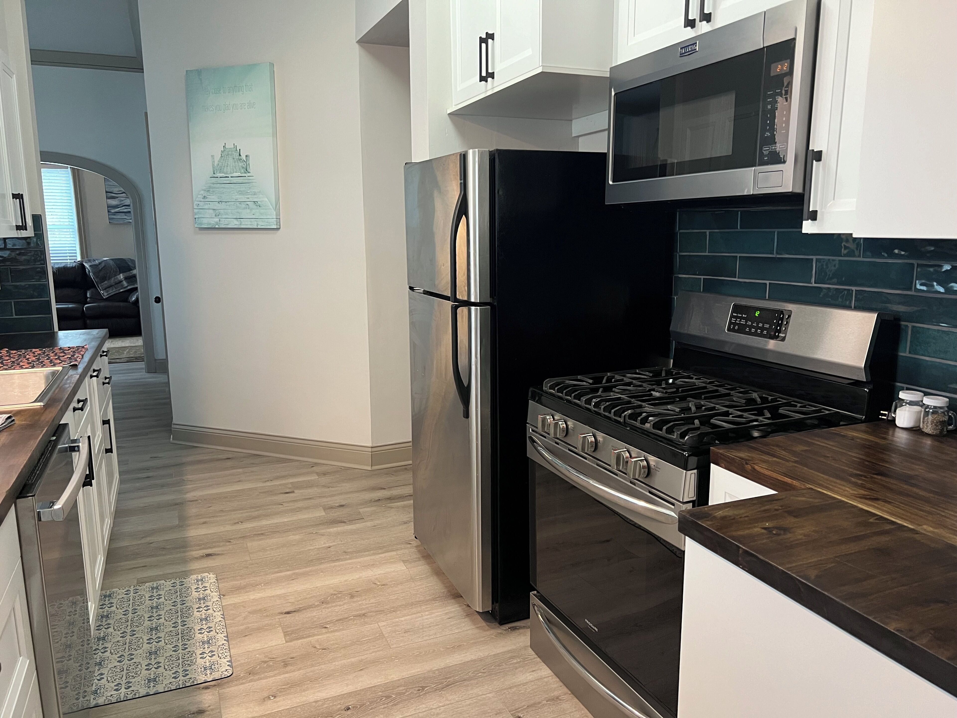 Een moderne keuken met roestvrijstalen apparatuur, een houten aanrecht en een betegelde spatwand.