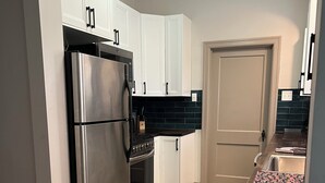 Una cocina moderna con gabinetes blancos, electrodomésticos de acero inoxidable y un salpicadero oscuro.