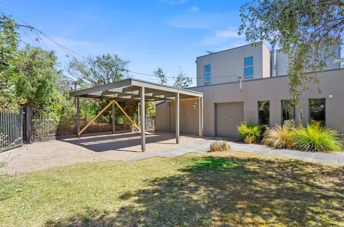 A modern building with a covered patio area, a fenced yard, and a well-maintained lawn.
