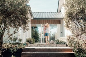 A modern house with a glass door entrance, surrounded by greenery.