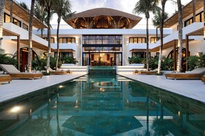 A modern hotel with a central pool, multiple balconies, and lush landscaping. - Baliwood Bingin (Pecatu)