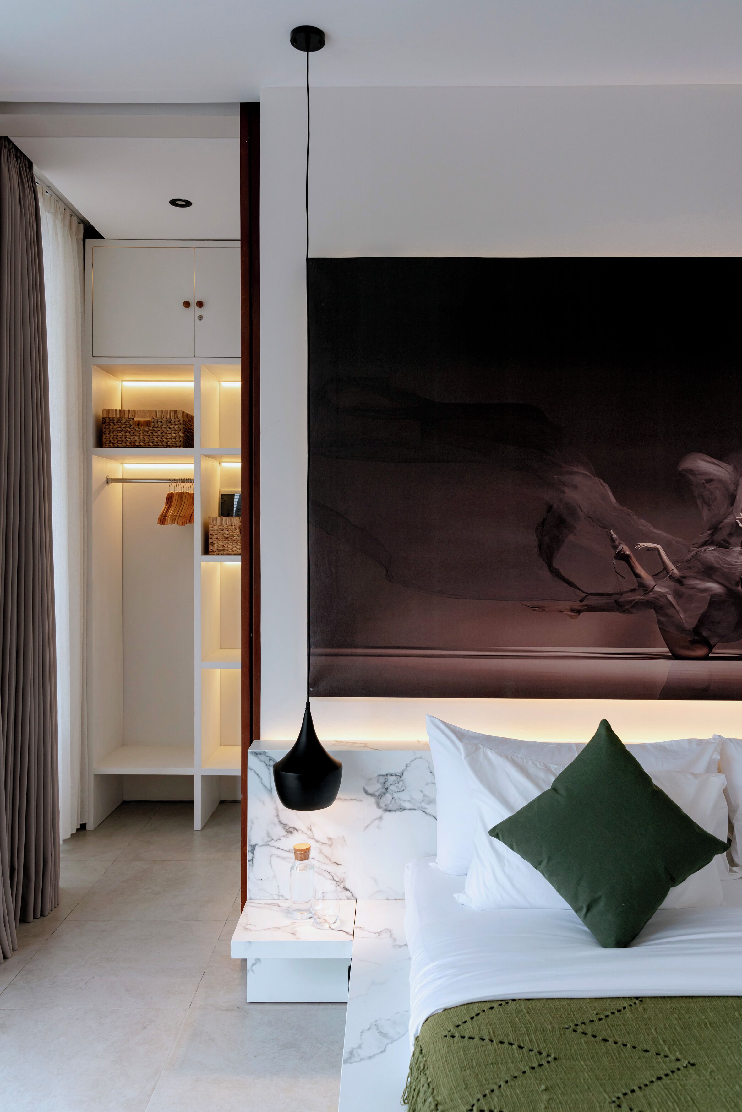 Een moderne slaapkamer met een bed, nachtkastje, kledingkast en een groot abstract schilderij aan de muur.