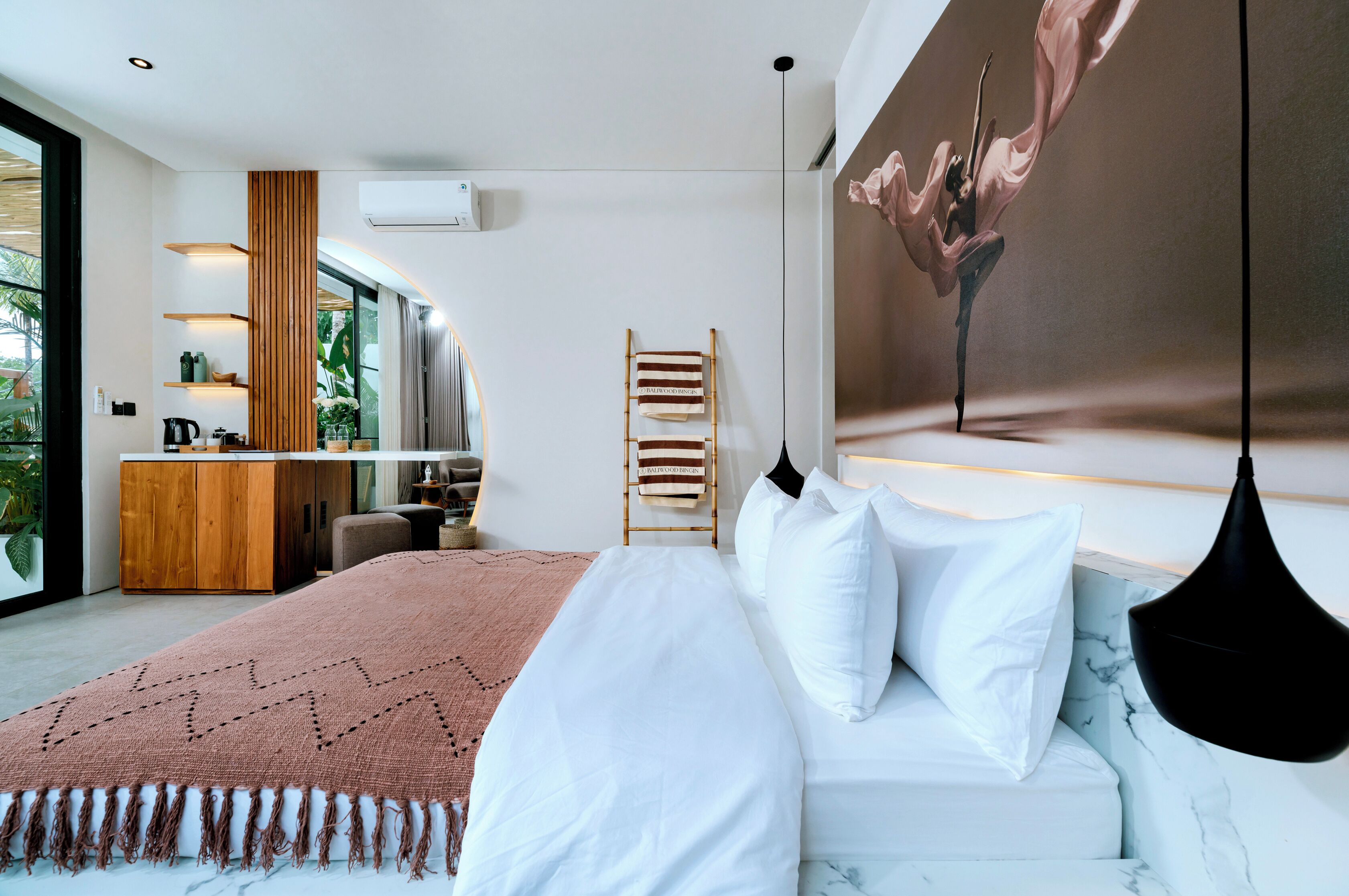 Een moderne slaapkamer met een groot bed, een houten garderobe, een zithoekje en uitzicht op het landschap.