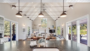 Una cocina amplia con una isla grande, elegantes lámparas colgantes y vistas al exterior.