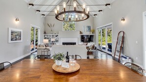 Amplia sala de estar con una mesa de comedor de madera, un candelabro y una chimenea.