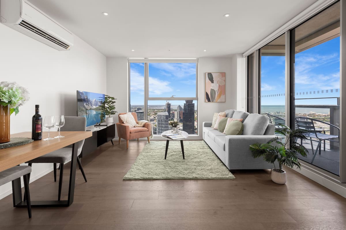 A modern living room with a dining area, large windows, and a city view.