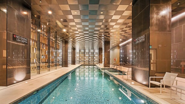 An indoor swimming pool with a checkered ceiling, glass walls, and a sign indicating no diving. - 888 Collins (Docklands)