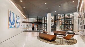 A spacious lobby with modern seating, large windows, and abstract wall art. - 888 Collins (Docklands)
