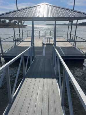 Un muelle de madera que conduce a una zona cubierta con una mesa y bancos.