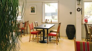 A dining area with a table, chairs, and a large vase. - Holiday Home With Nature View (Gørlev)