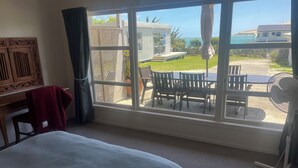 Een slaapkamer met een groot raam, een bed, een bureau en een stoel.
