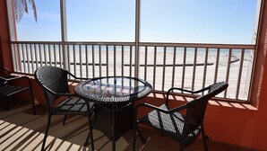 A balcony with a glass table and chairs, overlooking a beach. - Casa Playa Resort #102 King Suite Beach Front - "Starfish" (Fort Myers Beach)
