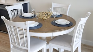 Un comedor con una mesa redonda, sillas blancas y un espejo en la pared.