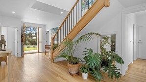 A spacious interior with a wooden staircase, potted plants, and a view of the outdoors. - The White House - 6 Bennett Street (CARRICKALINGA)