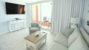 Ein modernes Wohnzimmer mit Flachbildfernseher, grauem Sofa, Holztisch und weißem Konsolentisch mit Schubladen.