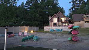 Una cabaña junto al lago con terraza, mobiliario exterior y un cobertizo para botes.