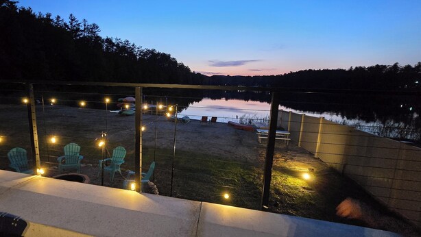Terraza frente al lago con luces cálidas, sillas y vistas al lago al anochecer.
