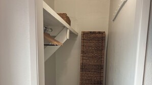 Un pasillo estrecho con suelo de madera, pared blanca y separador de tela tejido.