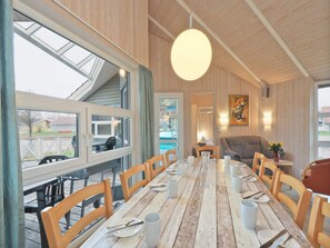 A dining area with a long wooden table, wooden chairs, and a hanging light fixture. - 4 Star Holiday Home in Ottendorf (Otterndorf)