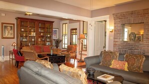 A spacious living room with a fireplace, a large wooden bookcase, and comfortable seating.