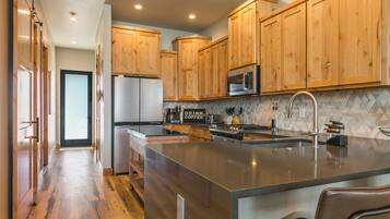 A modern kitchen with wooden cabinets, stainless steel appliances, and a large island.