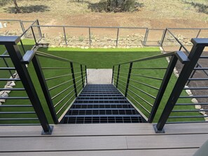 A staircase leading down to a green area with a metal railing.