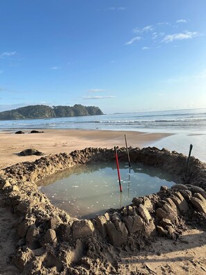 Uma praia arenosa com um pequeno corpo d'água e duas varas de pesca.