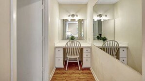 A narrow hallway with a vanity and mirror, wooden floor, and white walls. - Coastal Comfort 4BR in Stuart FL (Stuart)