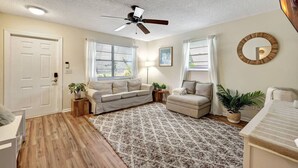 A well-lit living room with a ceiling fan, two sofas, a patterned rug, and a wooden floor. - Coastal Comfort 4BR in Stuart FL (Stuart)