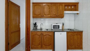 Eine Küche mit Holzausstattung, einer Mikrowelle, einem Spülbecken und einem Kühlschrank.