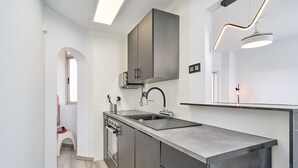 Una cocina moderna con encimera de acero inoxidable, horno empotrado y un mueble grande de color gris sobre el lavabo.