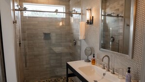 A modern bathroom with a glass-enclosed shower, a double sink vanity, and a large mirror.