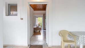 Corredor que leva a um quarto com uma cama e vista para o exterior.