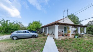Uma casa térrea com fachada branca, telhado de telhas e entrada com calçada.