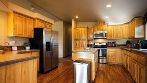Una cocina moderna con armarios de madera, electrodomésticos de acero inoxidable y una isla central.